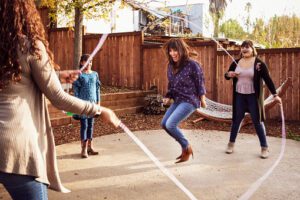 A mom jumping rope with kids in the backyard